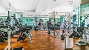 Uma academia com equipamentos de cardio, aparelhos de musculação e espelhos nas paredes.