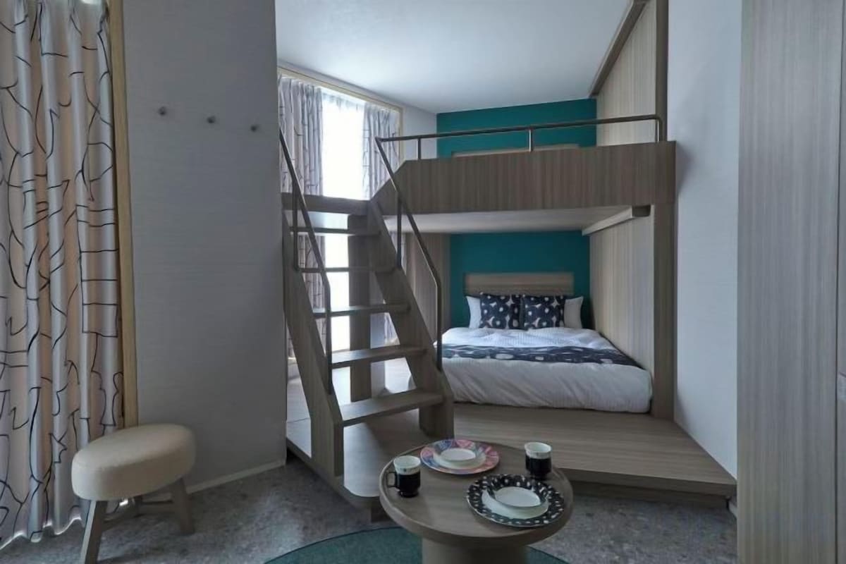 A compact room with bunk beds, a small table with cups, and a staircase.