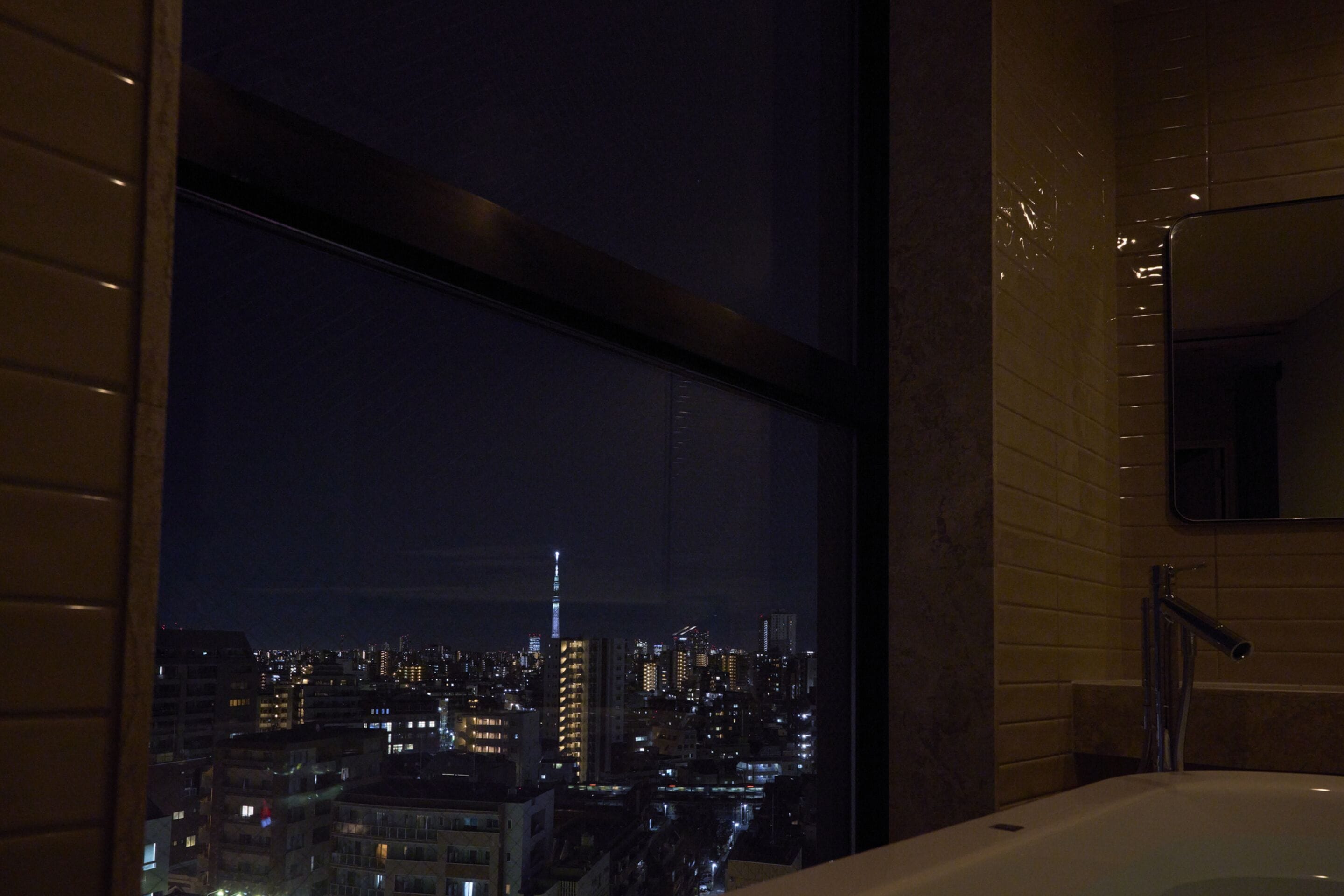 Ein modernes Badezimmer mit einem großen Fenster mit Blick auf eine nächtliche Skyline.