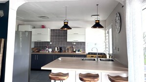 Una cocina moderna con una isla central, luces colgantes y un reloj en la pared.