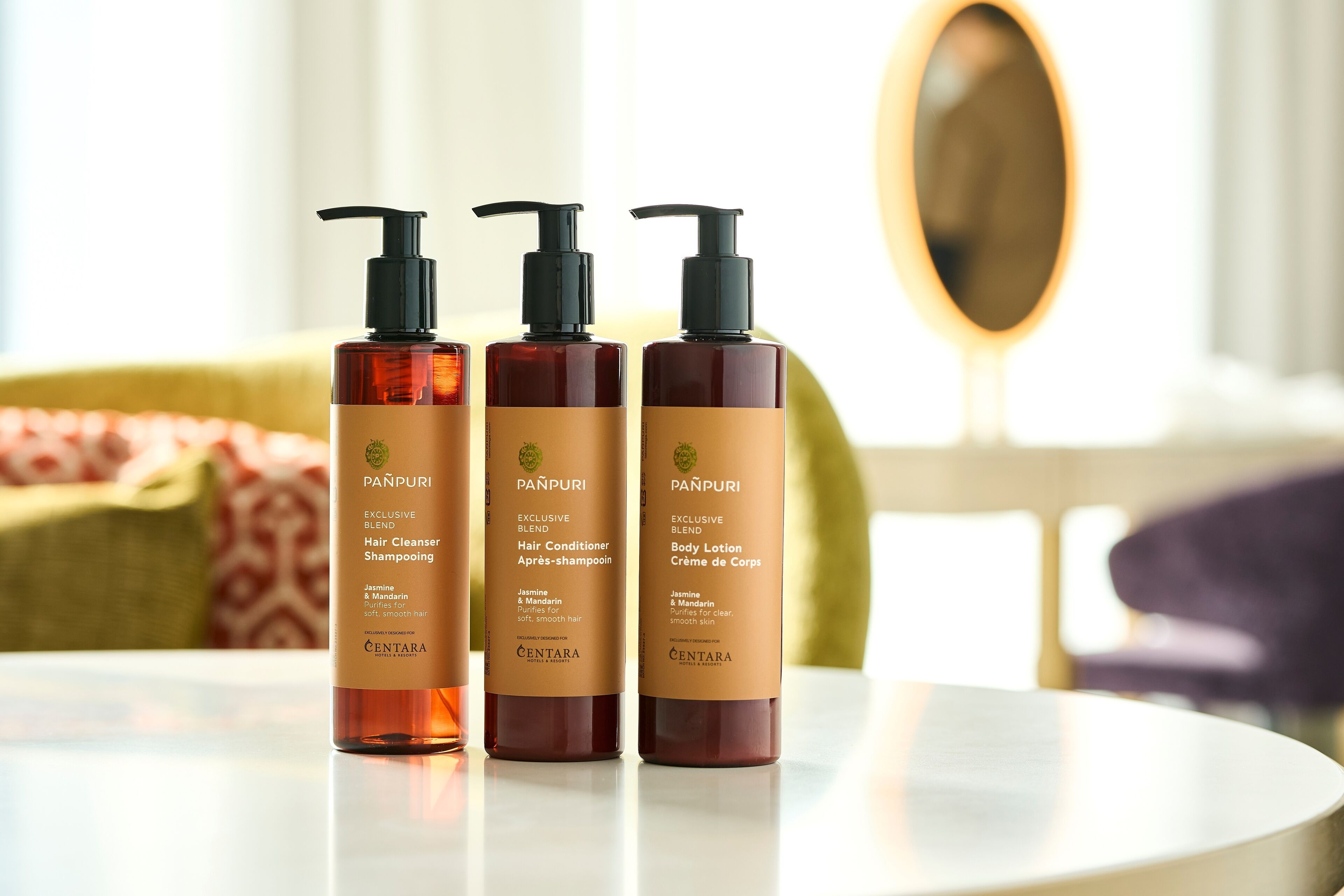 Three bottles of Centara hair and body care products on a table.