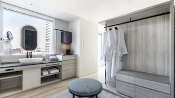 Un baño moderno con un espejo grande, un lavamanos redondo, un mueble de tocador con espacio de almacenamiento, un taburete redondo y una ducha a ras de suelo con pared de paneles de madera.