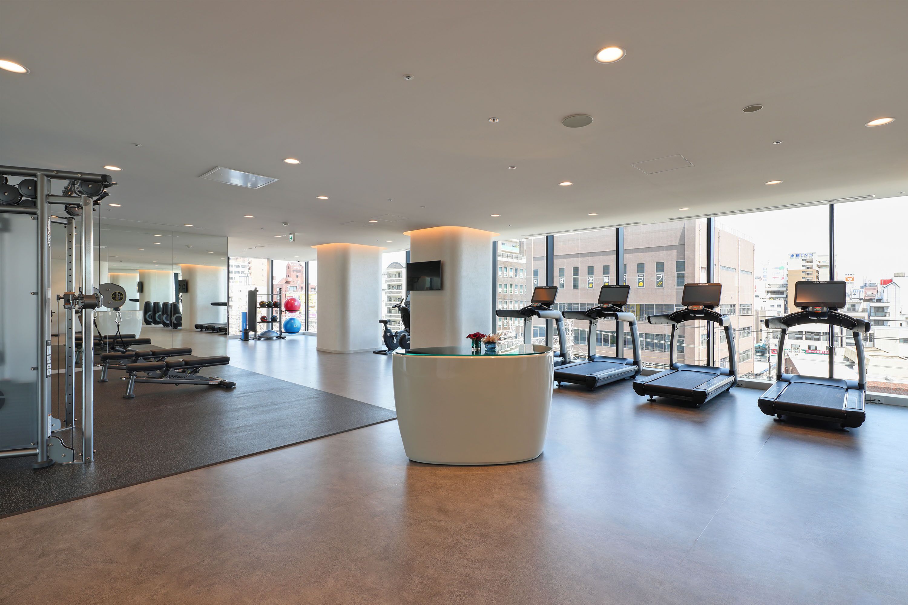 A modern gym with treadmills, weight machines, and a reception desk.