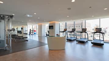 A modern gym with treadmills, weight machines, and a reception desk.