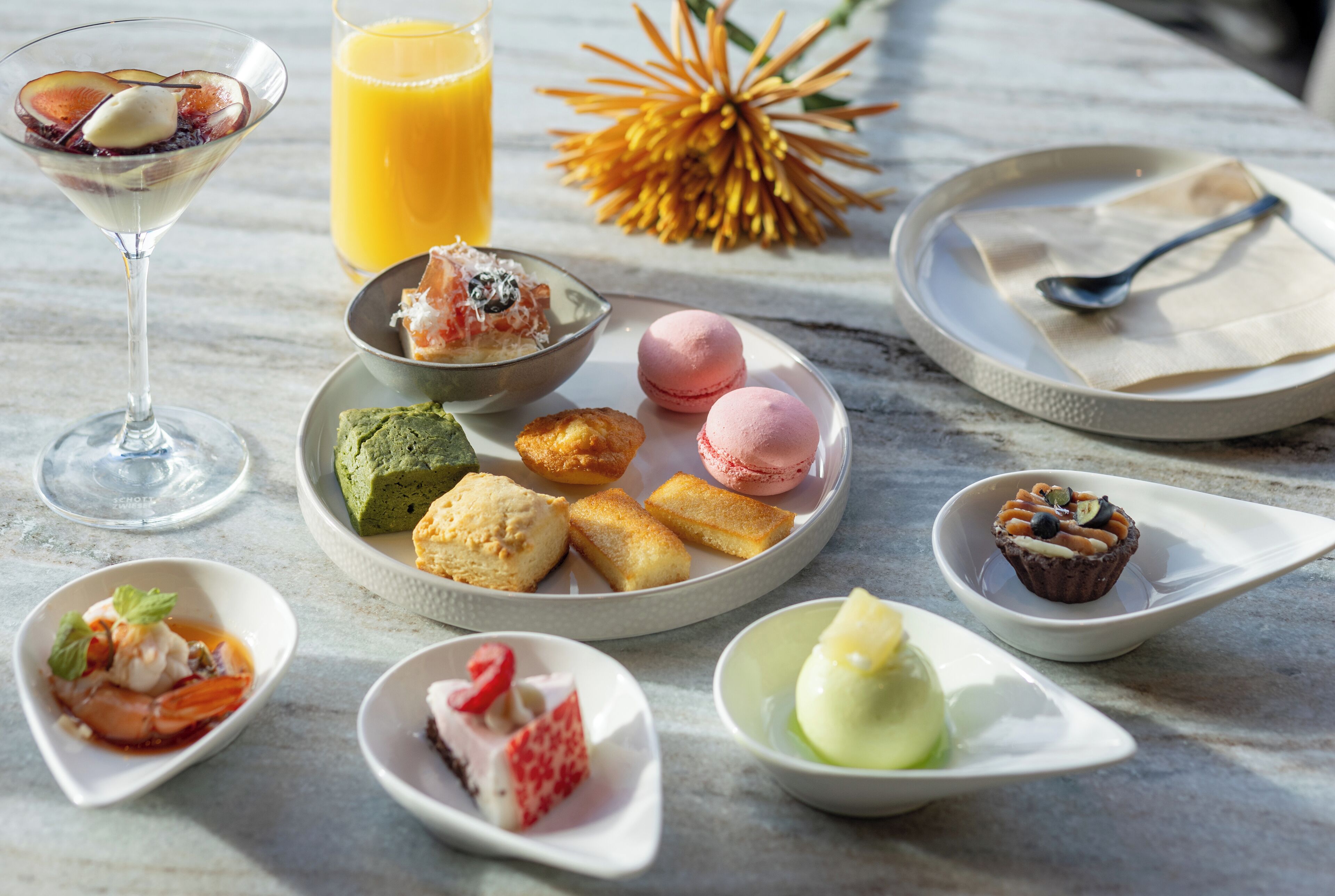 A variety of desserts and beverages on a marble table.