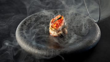 A dish with a garnish on a plate surrounded by smoke.