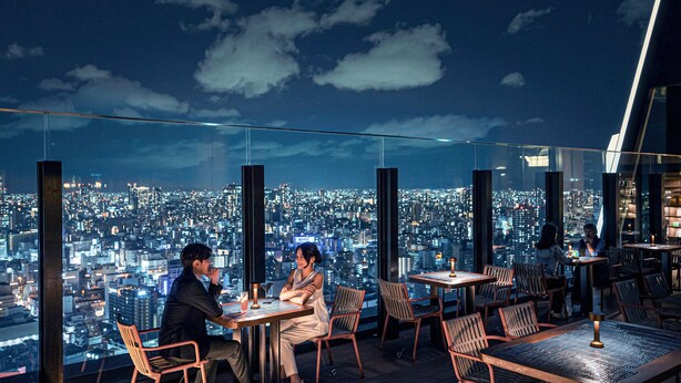Un restaurante en la azotea con mesas y sillas, que ofrece vistas panorámicas de la ciudad.