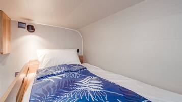Una cama individual con una colcha azul estampada con flores, una almohada blanca y un cabecero de madera.