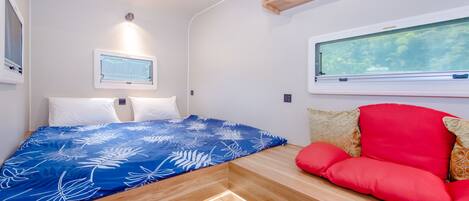 A bedroom with a bed, a window, and a built-in bench with cushions.