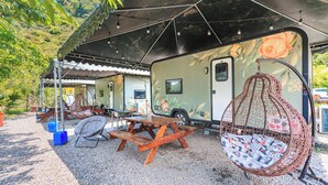 A recreational vehicle with a covered picnic area, a hanging chair, and a table. - Tai Ping Shan Inn (Datong)