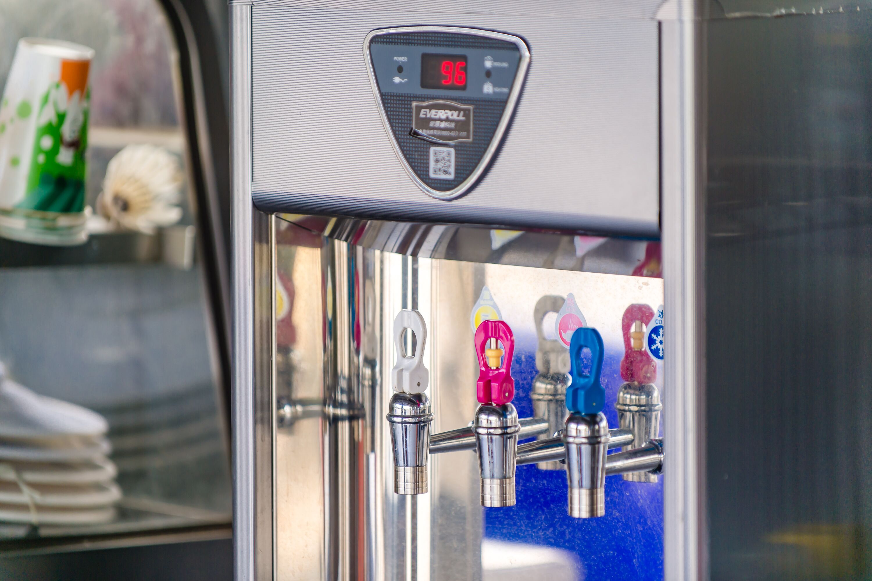 Ein Wasserspender mit digitaler Anzeige, die 96 anzeigt, und einem QR-Code.