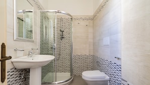 Une salle de bain avec une douche à parois de verre, un lavabo et des toilettes.