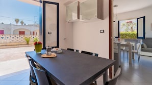Un espace repas moderne avec une longue table, des chaises et un vase de fleurs.