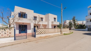 Un immeuble résidentiel moderne à la façade blanche, aux volets bleus et à l’entrée sécurisée par un portail.