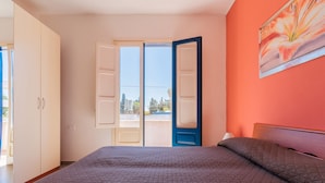 Une chambre à coucher comprenant un lit, une armoire et une porte donnant sur un balcon extérieur.