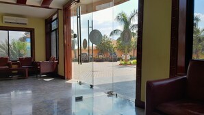 Un vestíbulo de hotel con piso de mármol, asientos de cuero y grandes puertas de vidrio que dan al exterior.