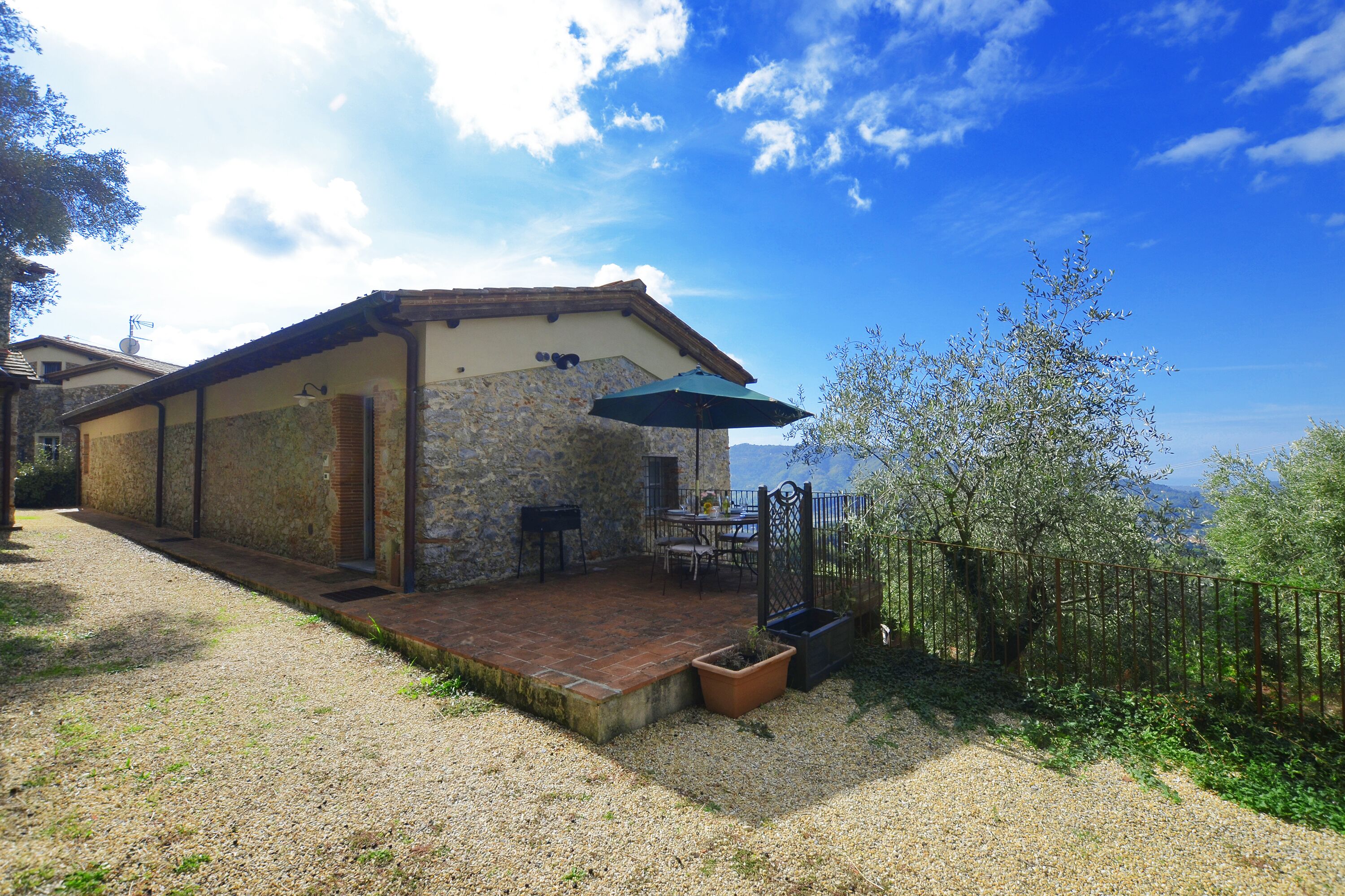 A stone building with a patio, outdoor seating, and a view of the sea.