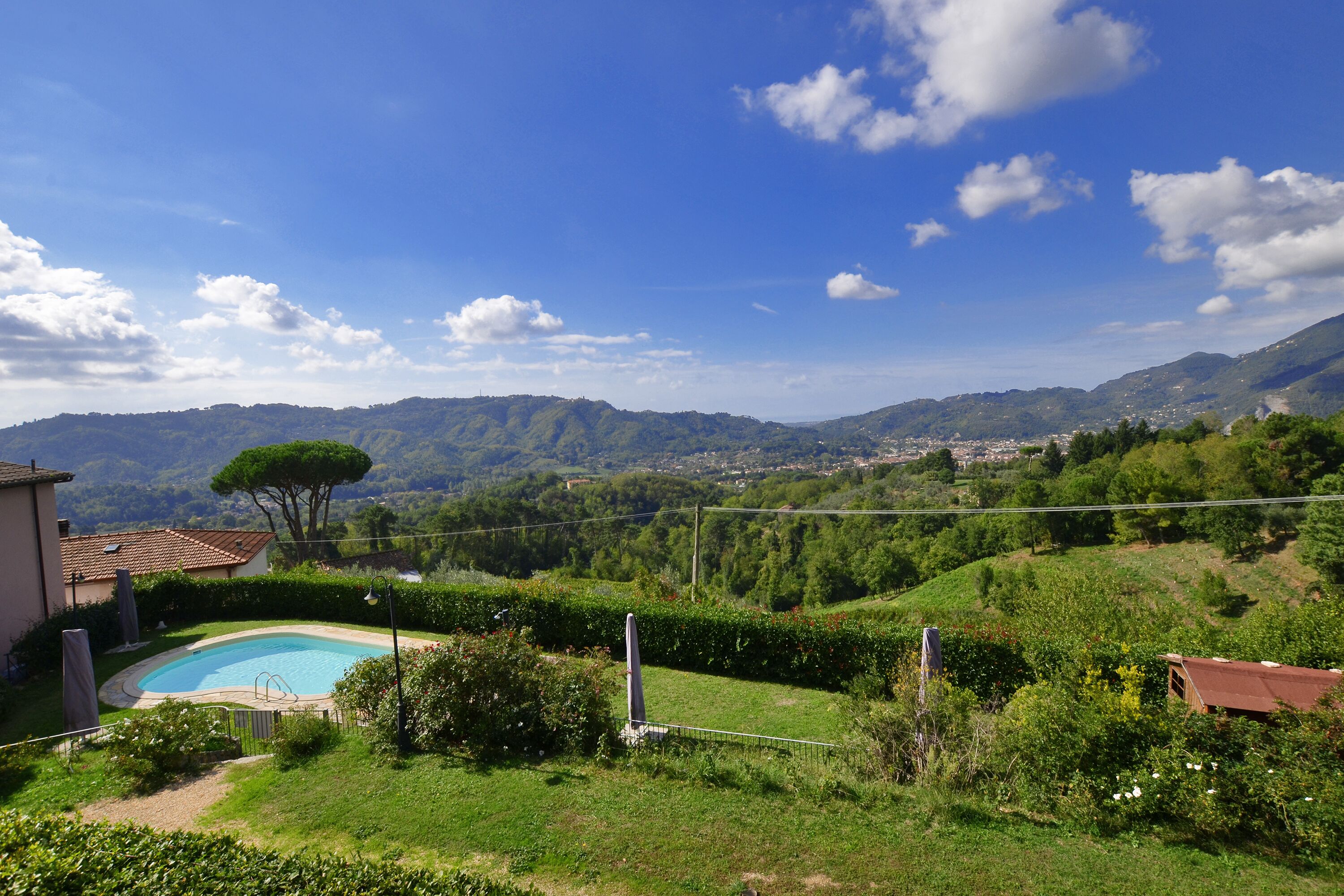 A residential area with a swimming pool, surrounded by lush greenery and mountains in the background.