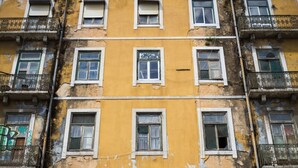 Un edificio de varios pisos con paredes amarillas y blancas, varios balcones y numerosas ventanas.
