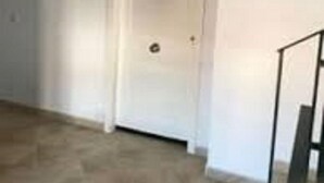 Una habitación con una puerta blanca, una ventana pequeña y piso de madera.