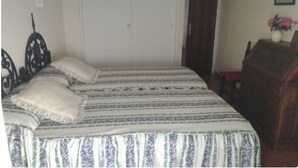 Un dormitorio con cama, armario, escritorio y silla.