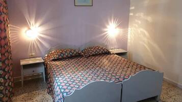 A bedroom with a bed, two bedside lamps, a nightstand, a wall-mounted picture, and a window.