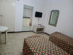 A room with a bed, a small table, a TV, and a mirror. - Rimel el corniche (Sousse)