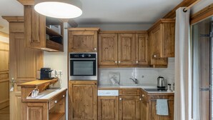 Una cucina con mobili in legno, forno a incasso, lavello e zona pranzo con tavolo e sedie.