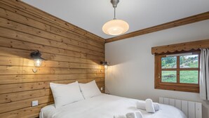 Una stanza con rivestimenti in legno, un letto, due luci a parete, una finestra con vista e una plafoniera.