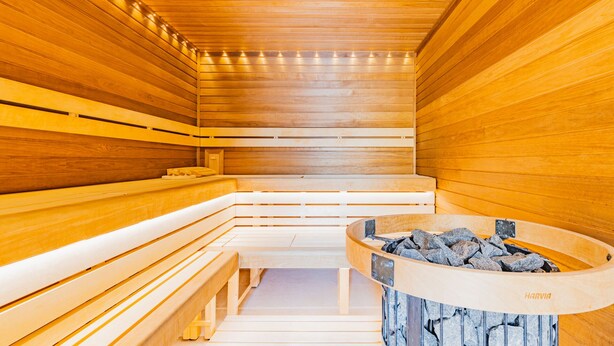 A sauna with wooden benches and a central stone basin. - Wellness penzion Lázně Kvilda (Kvilda)