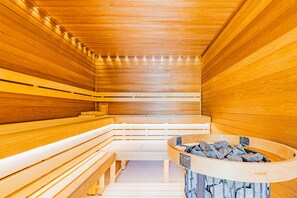 A sauna with wooden benches and a central stone basin. - Wellness penzion Lázně Kvilda (Kvilda)