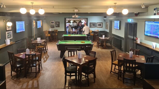 A billiards room with tables, chairs, and a pool table. There are multiple screens displaying content. - The Hen House (Cannock)