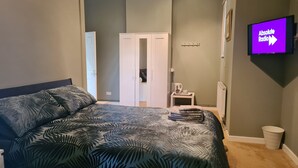 A bedroom with a bed, a wardrobe, a television, and a small table with a kettle and cup. - The Hen House (Cannock)