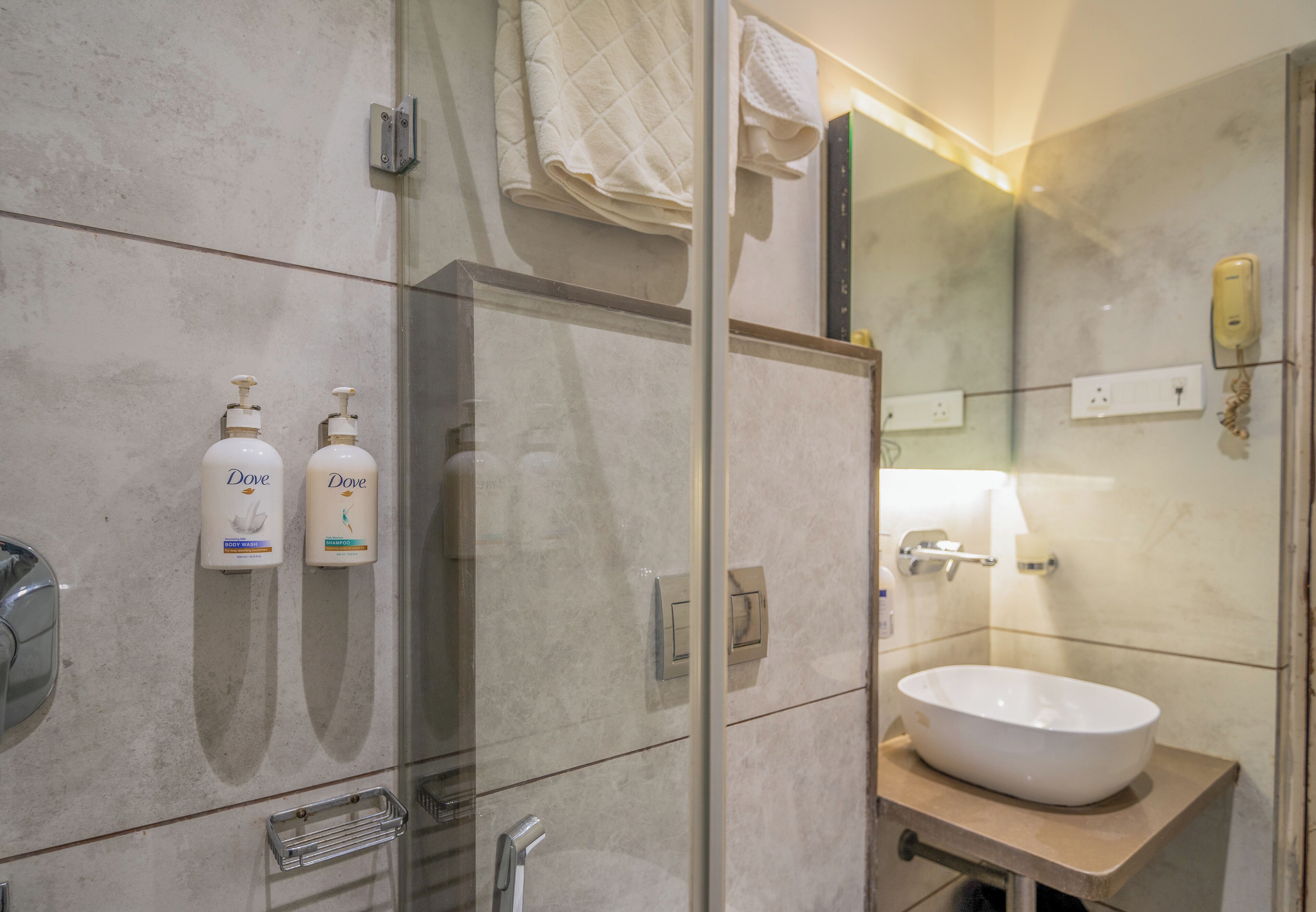 Un baño moderno con un espejo grande, un lavabo y dos dispensadores de jabón Dove.
