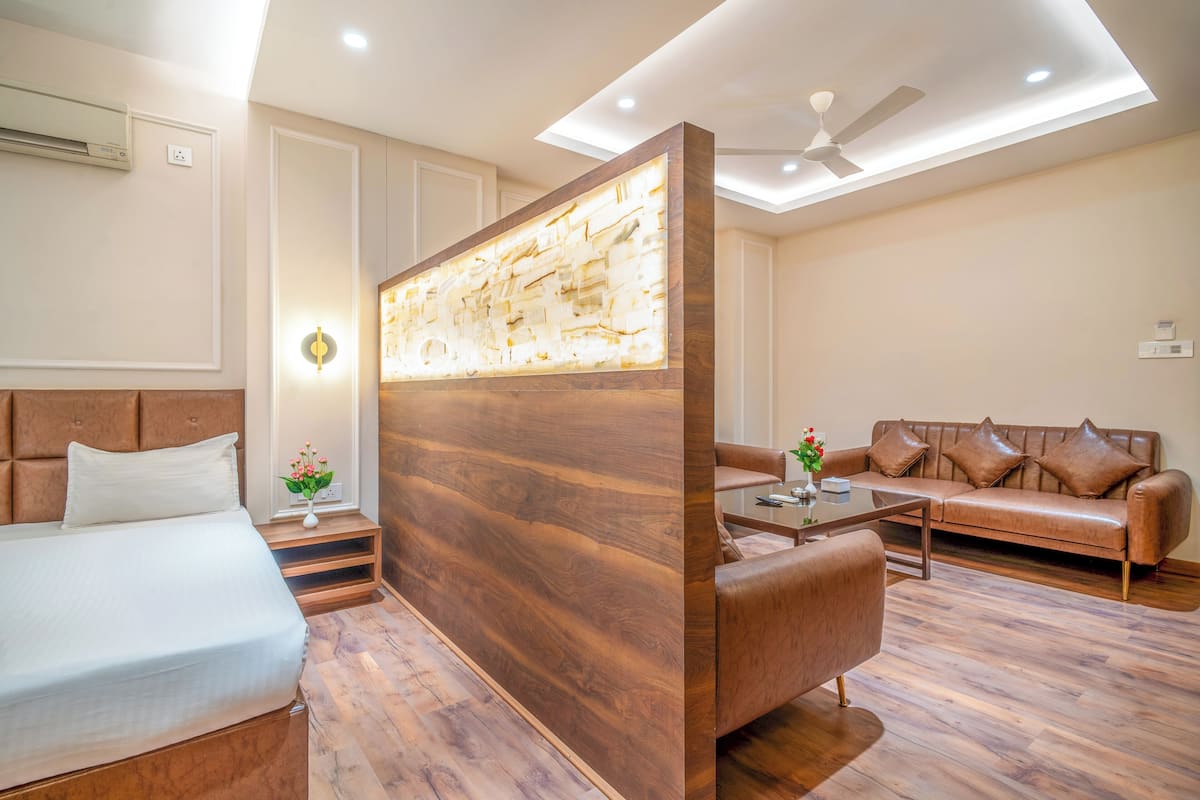 Una habitación de hotel moderna con una cama grande, un sofá, una mesa de centro y un separador decorativo.