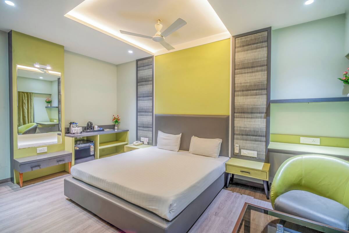 Una habitación de hotel moderna con una cama grande, un escritorio, una silla y un ventilador de techo.