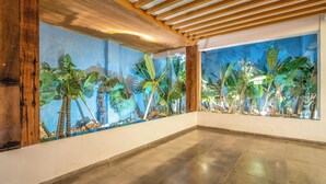 Amplia habitación con piso pulido, vigas de madera en el techo y un gran mural de plantas tropicales en la pared.