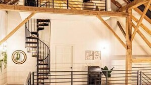 Ett rum i loftstil med ett träpanelat tak, en spiraltrappa och ett litet köksområde.