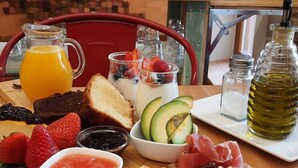A breakfast buffet with bread, cheese, fruits, and beverages. - La casa del médico - Hostería rural (Urda)