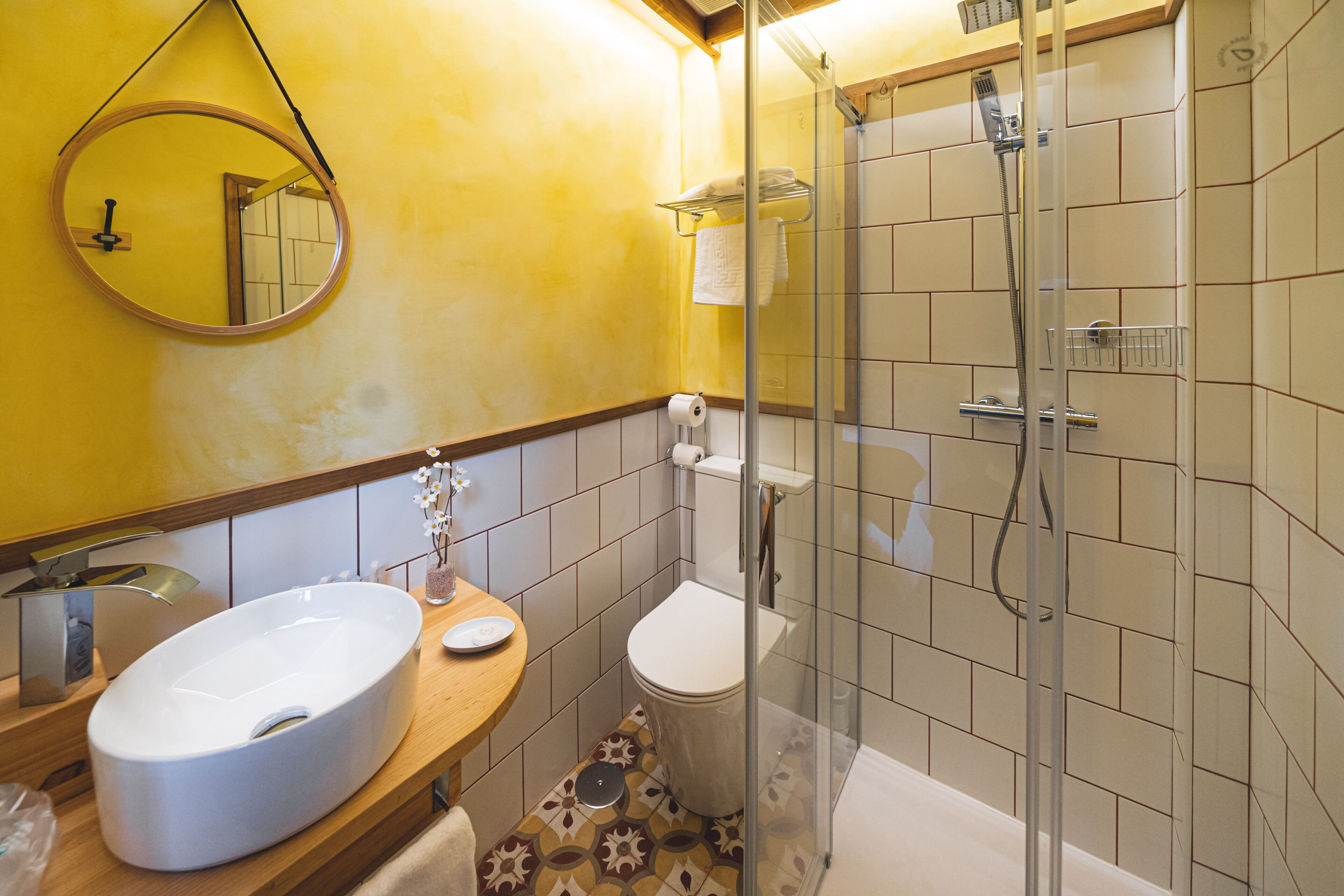 Un baño con un espejo redondo, un lavabo, un inodoro y una zona de ducha.