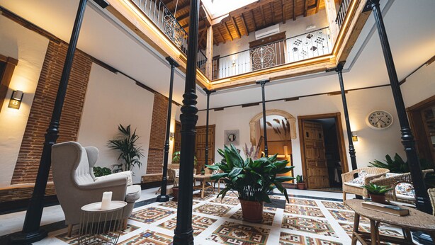 A spacious atrium with a high ceiling, a central staircase, and a patterned floor. - La casa del médico - Hostería rural (Urda)