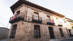 A two-story building with stone facade, balconies with wrought iron railings, and a tiled roof. - La casa del médico - Hostería rural (Urda)