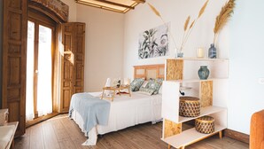 A bedroom with a wooden bed, a shelf with decorative items, and a painting on the wall. - La casa del médico - Hostería rural (Urda)