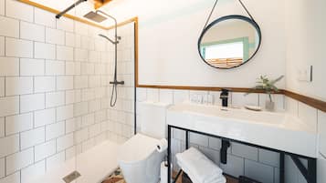 Un baño con ducha, inodoro, lavamanos y espejo.