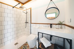 Un baño con ducha, inodoro, lavamanos y espejo.