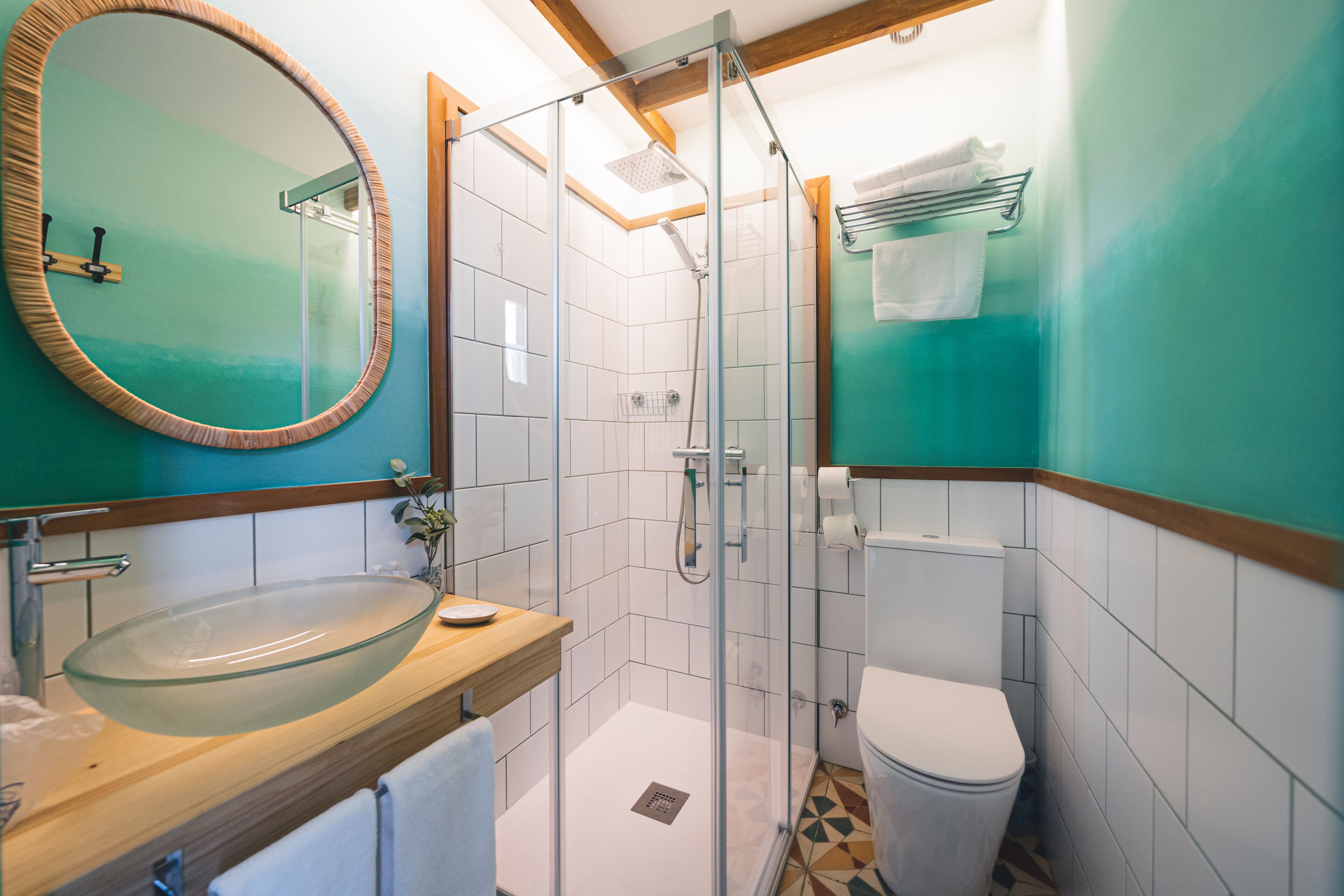 Een badkamer met een douchecabine van glas, een wastafel met een houten blad, een toilet en een spiegel met houten lijst.