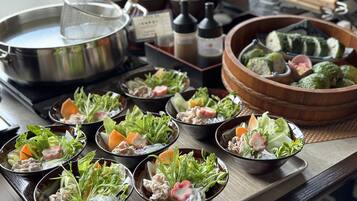 A table with various dishes, including bowls of salad and other food items, a pot, and a wooden bowl with vegetables.