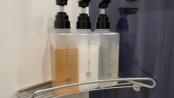 Un estante con tres botellas de champú, acondicionador y gel de baño.