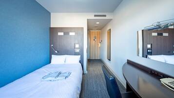 A hotel room with a bed, a desk with a telephone, a mirror, and a door leading to a hallway.