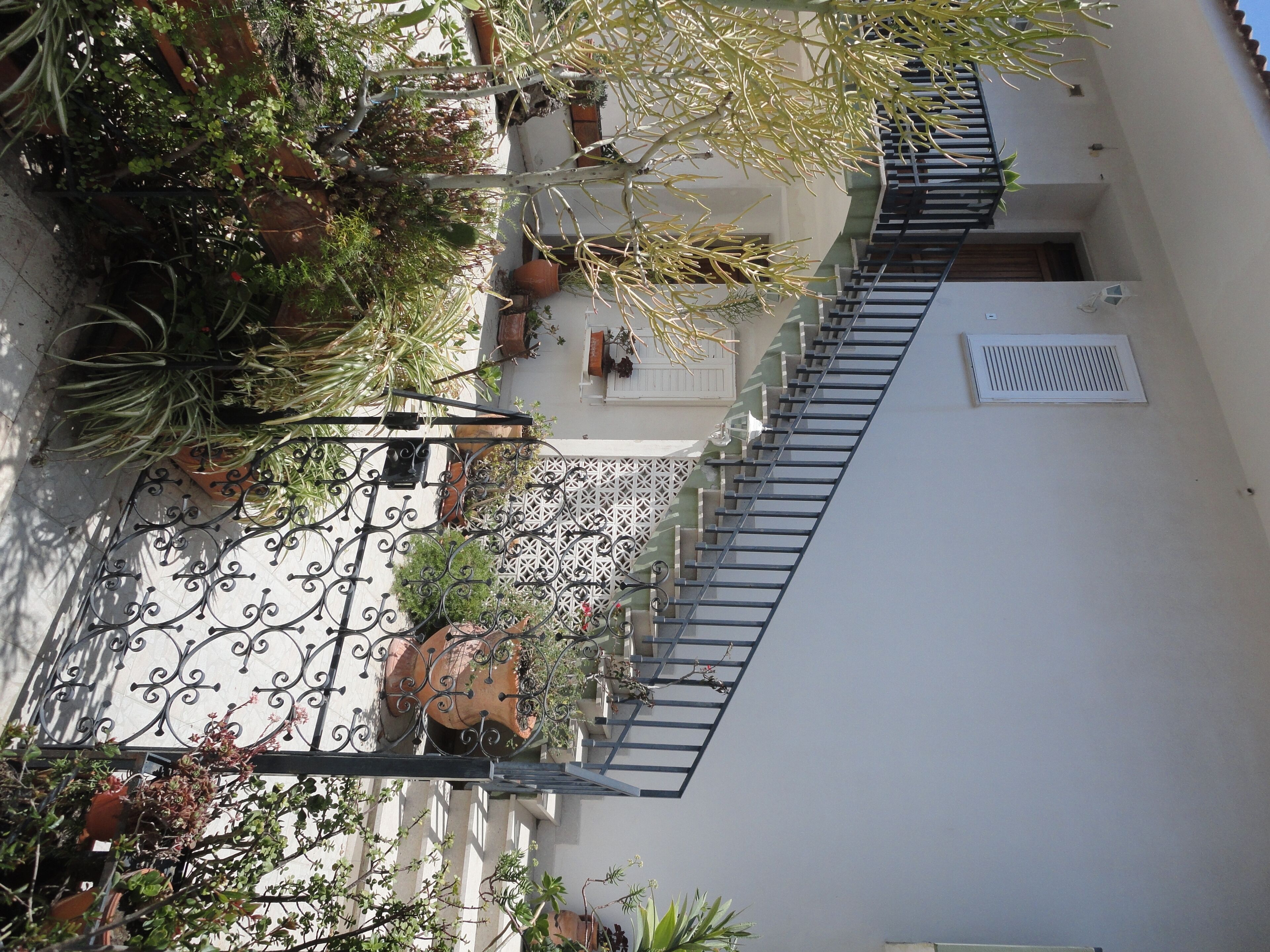 Ein Innenhof mit Treppe, Blumentöpfen und einem weißen Gebäude.